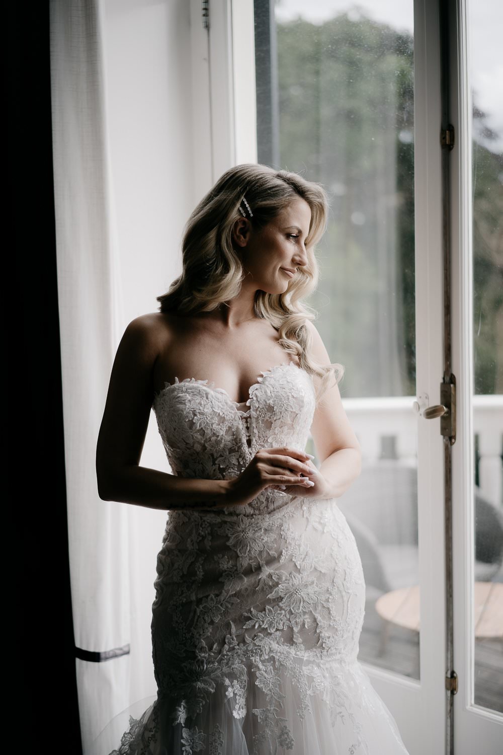 Michelle Jethro-059 - bride wearing mermaid wedding dress looking out window in amsterdam hotel room.jpg