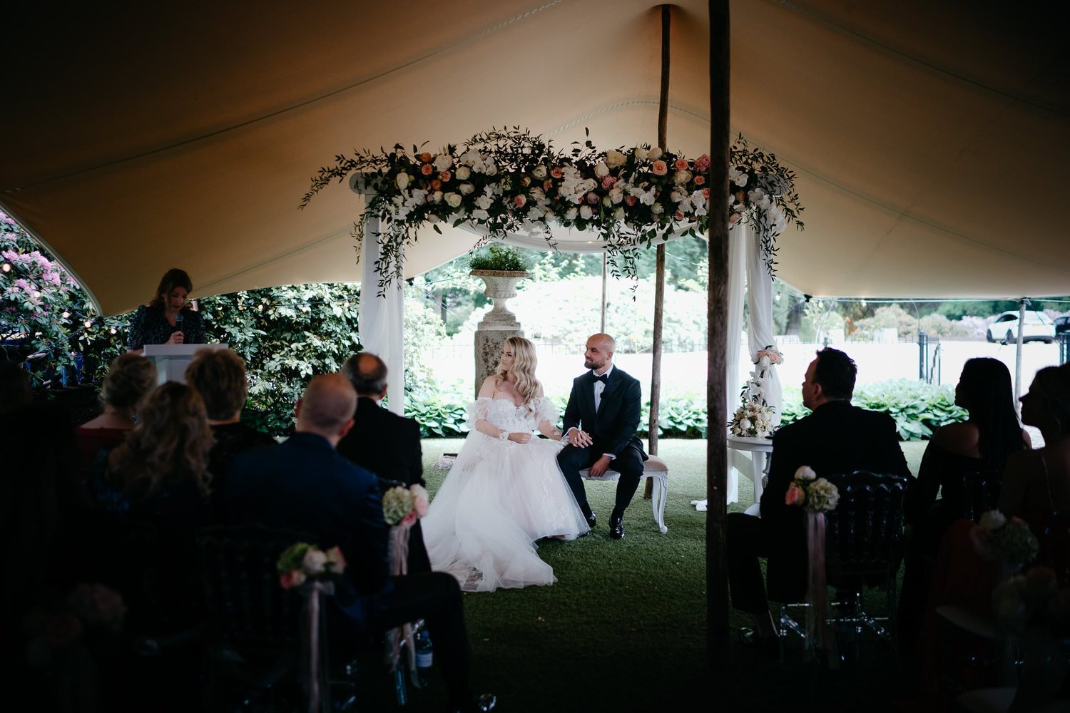 Michelle Jethro-091 - bride and groom holding hands during wedding ceremony under floral arch.jpg