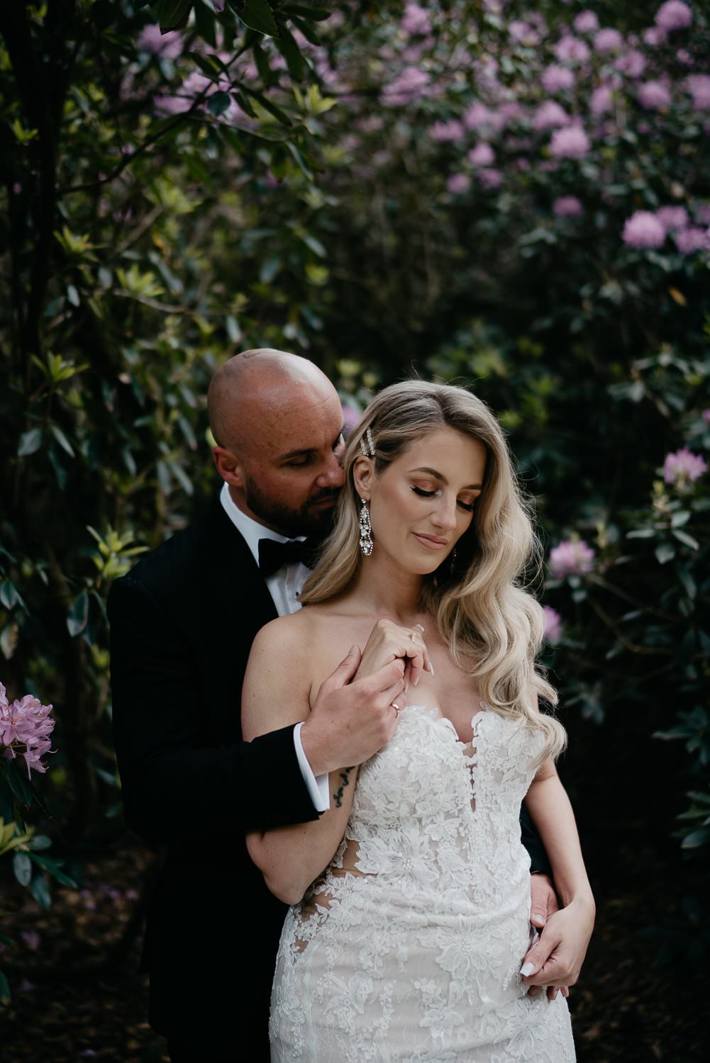 Michelle Jethro-208 - groom embracing bride wearing elegant white dress in lush garden setting.jpg
