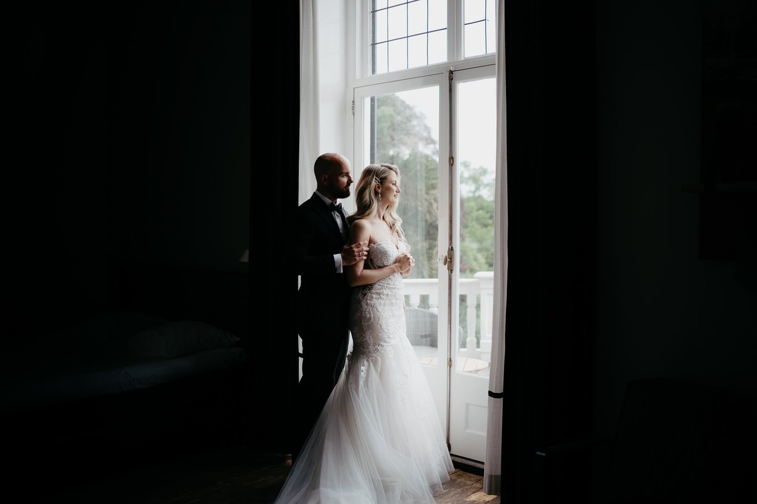 Michelle Jethro-210 - groom embracing bride while looking out window in amsterdam hotel room.jpg