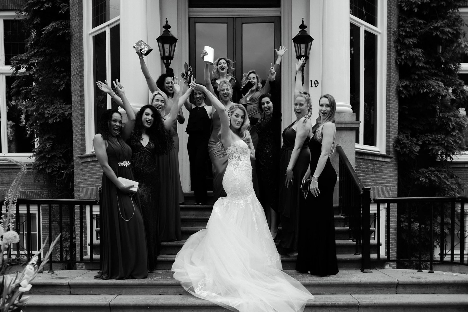 Michelle Jethro-224-2 - bride posing with bridesmaids cheering on building steps in amsterdam.jpg
