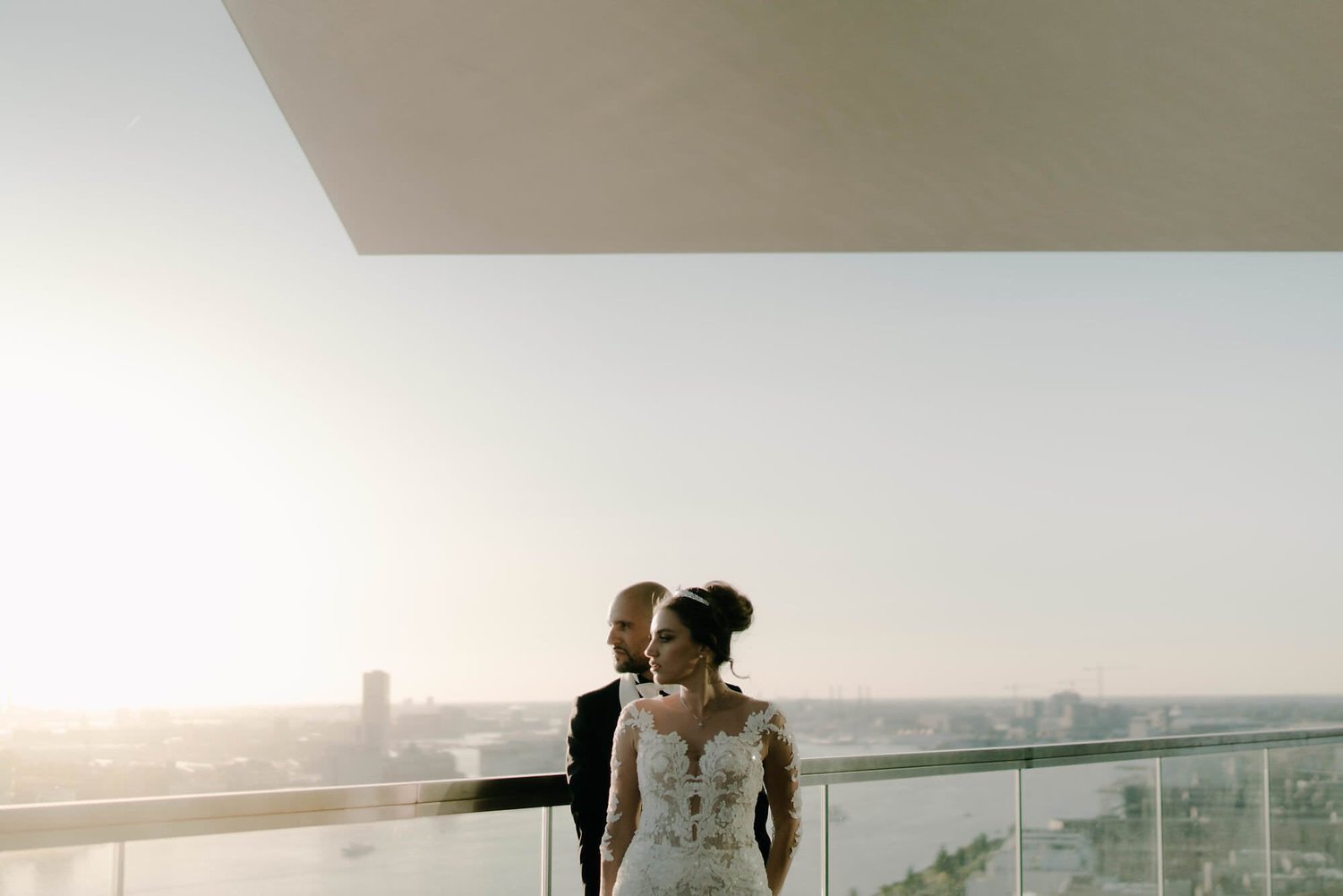 Kareline_Amir_333 - Bride and groom posing on balcony overlooking amsterdam at sunset during wedding photoshoot.jpg