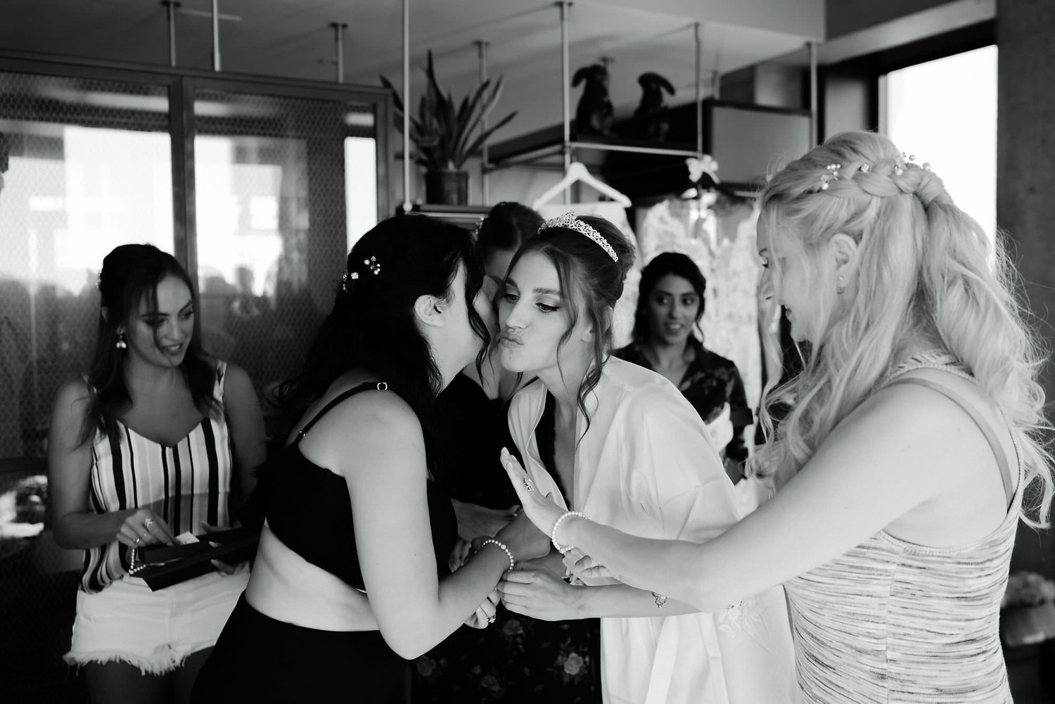 Kareline_Amir_025_2 - Bridesmaids kissing and hugging bride getting ready in loft.jpg