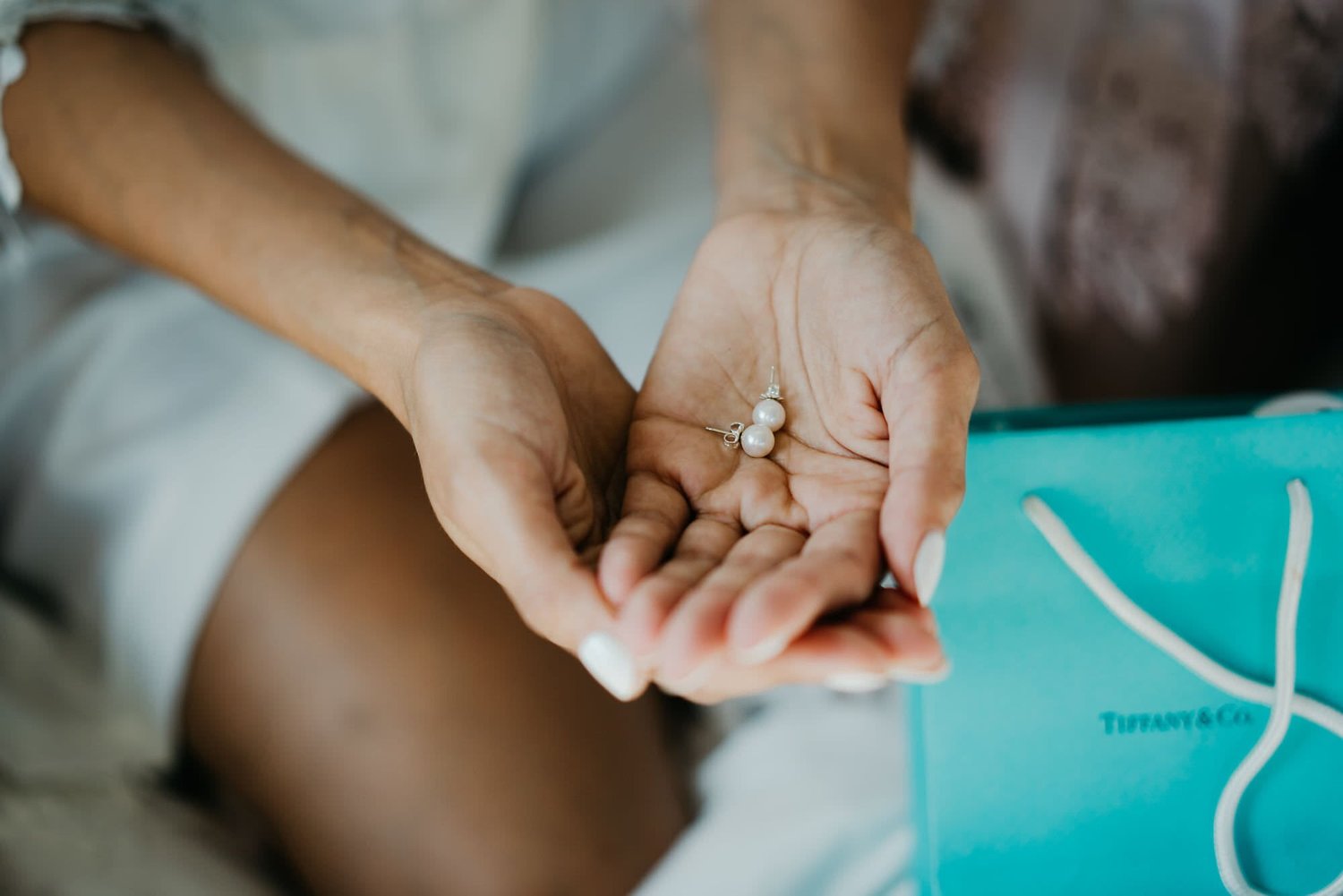 Kareline_Amir_038 - Bride holding pearl earrings near tiffany & co Gift bag.jpg