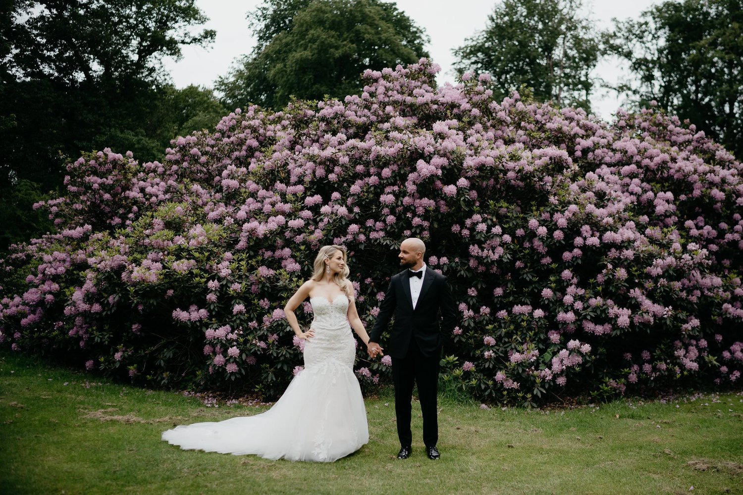 Michelle Jethro-199 - bride and groom holding hands in front of rhododendron bush in amsterdam park.jpg