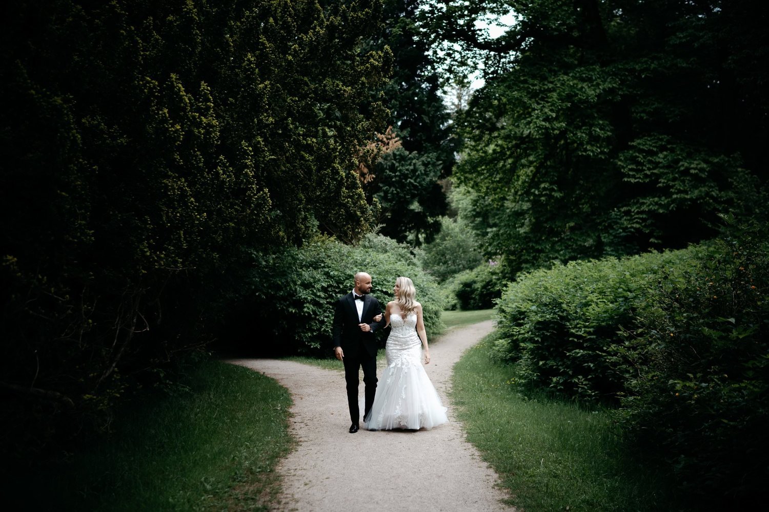 Bride and groom walking arm in arm down gravel path
